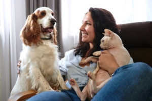 Uma mulher deitada em um sofá com um gato e um cão amam o conceito de animais de estimação